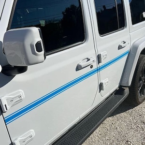 May include: White SUV with a blue stripe along the side. The vehicle has black tyres and a black running board. The side mirror is white. The door handles and door hinges are white.