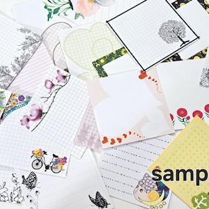 May include: Assortment of blank note cards with various designs, including floral patterns, checkered patterns, and a bicycle with a basket of flowers. The cards are white with black grid lines and some have a black border. One card has the word "sample" printed on it.
