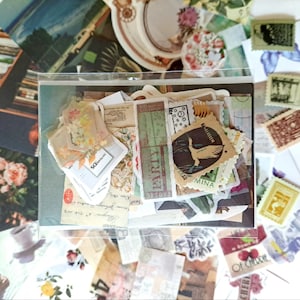May include: A collection of vintage-style ephemera, including stamps, labels, and paper scraps, arranged in a clear plastic sleeve. The items feature floral, botanical, and text designs in muted colors. Some pieces have text that reads "PARTY" and "OF CHERRIE".