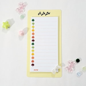 May include: A yellow notepad with a to-do list on the front. The notepad has a white background with a vertical line of colorful trees on the left side. The notepad is labeled "To Do List" at the top and "Note" at the bottom.