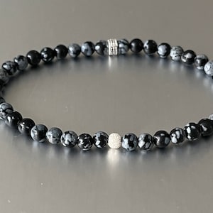 May include: A black and white snowflake obsidian beaded bracelet with silver accents.