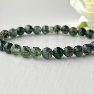 May include: A green moss agate beaded bracelet with a silver spacer bead.