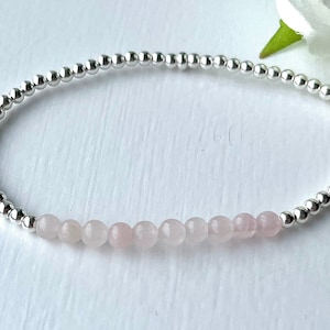 May include: A delicate bracelet featuring silver beads and a row of pale pink rose quartz beads.