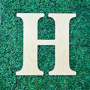 Op de afbeelding: Een grote, witte houten letter H, getoond tegen een achtergrond van groen kunstgras.