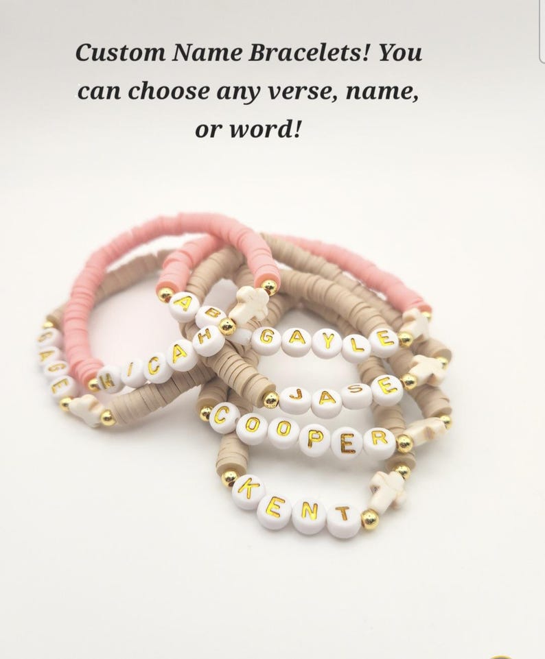 May include: A collection of beaded bracelets featuring pink and beige clay discs, gold-tone spacer beads, and white letter beads spelling names like GAGE, MICAH, GAYLE, JASE, COOPER, and KENT, with small white cross charms and the text Custom Name Bracelets!