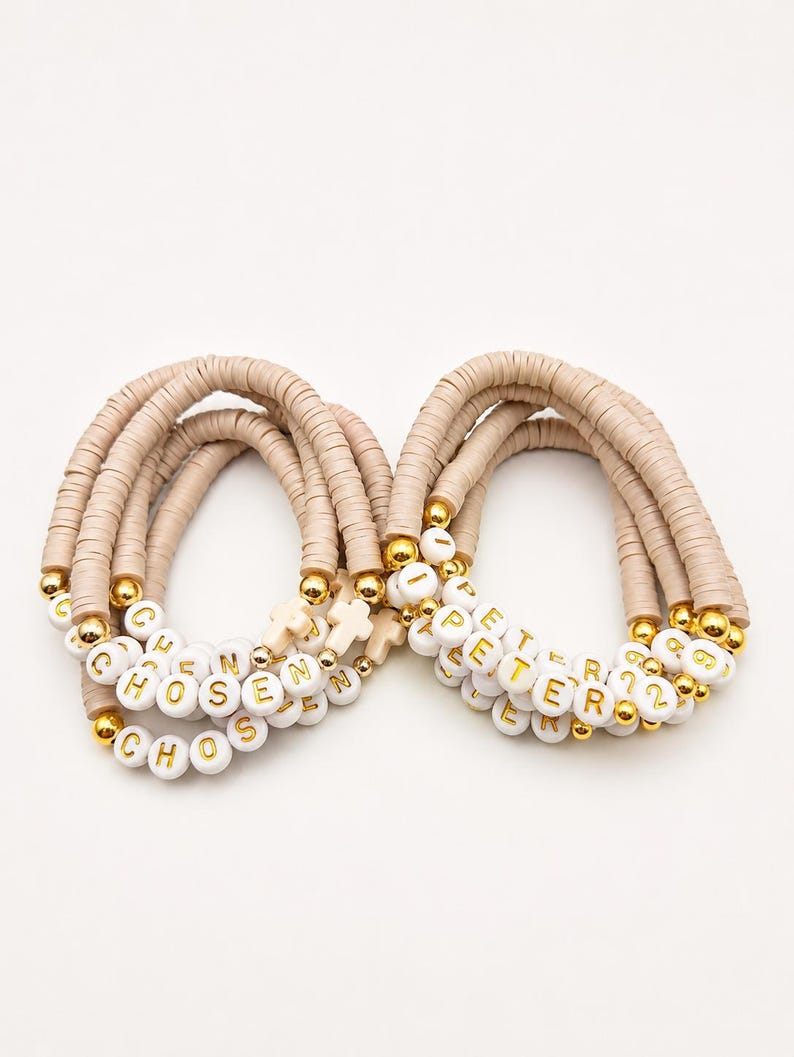 May include: Two stacks of beaded bracelets made with beige clay disc beads, gold-toned metallic spacer beads, and white round letter beads. One stack spells CHOSEN and features a small cross charm, while the other spells PETER 12.
