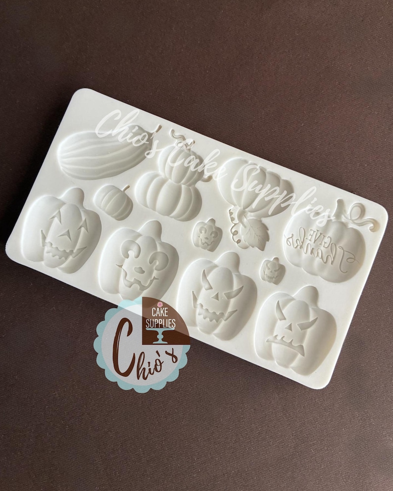 May include: A white silicone mold featuring various Halloween-themed pumpkin designs. The mold includes pumpkins with carved faces, a watermelon, and the text "Chio's Cake Supplies".