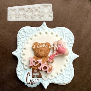 Pu&ograve; includere: Un orsacchiotto di peluche marrone che tiene un palloncino rosa con le parole "Ti amo" in lettere rosa. L'orsacchiotto &egrave; su uno sfondo bianco con un design a pizzo blu e bianco.