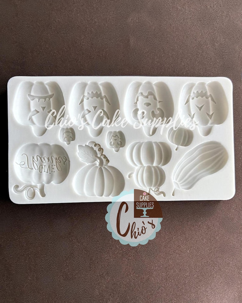 May include: A white silicone mold featuring various pumpkin designs, including jack-o'-lantern faces, stacked pumpkins, and a gourd. The mold is labeled with the text "Chio's Cake Supplies".