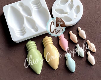 Könnte beinhalten: Ein Set Silikonformen zum Herstellen von Glühbirnen-förmigen Kuchendekorationen. Die Formen sind weiß und werden mit mehreren Glühbirnen-förmigen Dekorationen in verschiedenen Pastellfarben gezeigt.