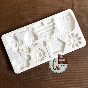 Puede incluir: Molde de silicona blanco con 10 formas diferentes, incluyendo una abeja, un panal, un girasol y una olla de miel. El molde es para hacer decoraciones de pasteles.