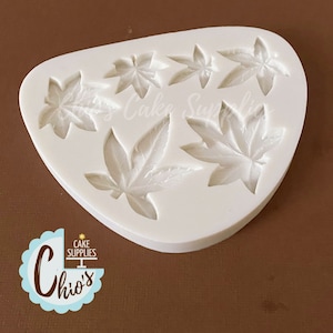 May include: White silicone mold with six leaf shapes. The mold is designed to create edible decorations for cakes and other desserts.