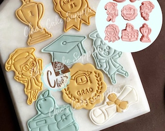 May include: A set of 10 graduation themed cookie cutters. The cutters are made of a light pink plastic and feature various graduation-related designs, including a graduation cap, a diploma, a book stack, an apple, a trophy, and a student with a graduation cap. The cutters are arranged in a circle on a white background.