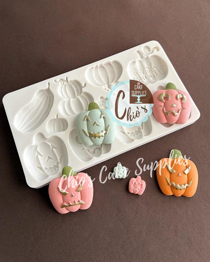 May include: A white silicone mold with various pumpkin shapes and several finished, colorful pumpkin decorations. The pumpkins are in shades of pink, orange, and green, with gold accents. The mold has the text "Chio's Cake Supplies".