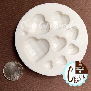 May include: White silicone mold with eight heart-shaped cavities. The hearts have a diamond pattern. The mold is on a brown surface.  "Chic Cake Supplies" is printed on the mold.