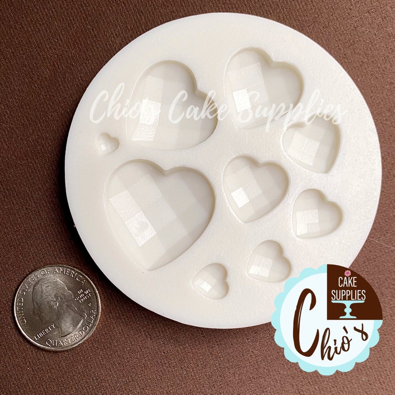 May include: White silicone mold with eight heart-shaped cavities. The hearts have a diamond pattern. The mold is on a brown surface.  "Chic Cake Supplies" is printed on the mold.