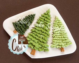 Könnte beinhalten: Drei grüne Weihnachtsbaum-förmige Formen mit braunen Stämmen werden auf einem weißen Tablett präsentiert. Die Formen dienen der Kuchendekoration. Das Bild enthält den Text "Chio's Cake Supplies".