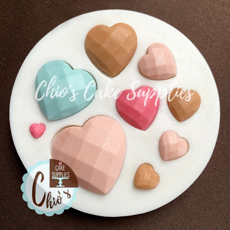 May include: Silicone mold with eight heart-shaped cavities. The hearts have a geometric, faceted design. The mold is white and the hearts are in various colors, including pink, blue, and brown.