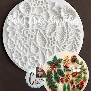 May include: A white circular silicone mold featuring various botanical shapes including pinecones, holly leaves, berries, and foliage. The text Chio's Cake Supplies is visible on the mold and a logo. A circular inset shows finished decorations.