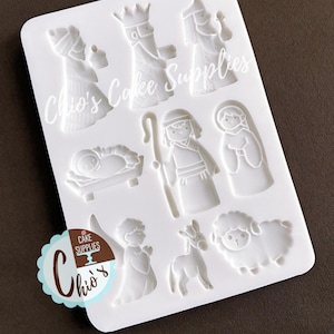May include: A white rectangular silicone mold featuring recessed cavities for a nativity scene, including figures of the three wise men, a baby in a manger, a shepherd with a staff, an angel, a donkey, and a sheep. The text Chio's Cake Supplies is visible.