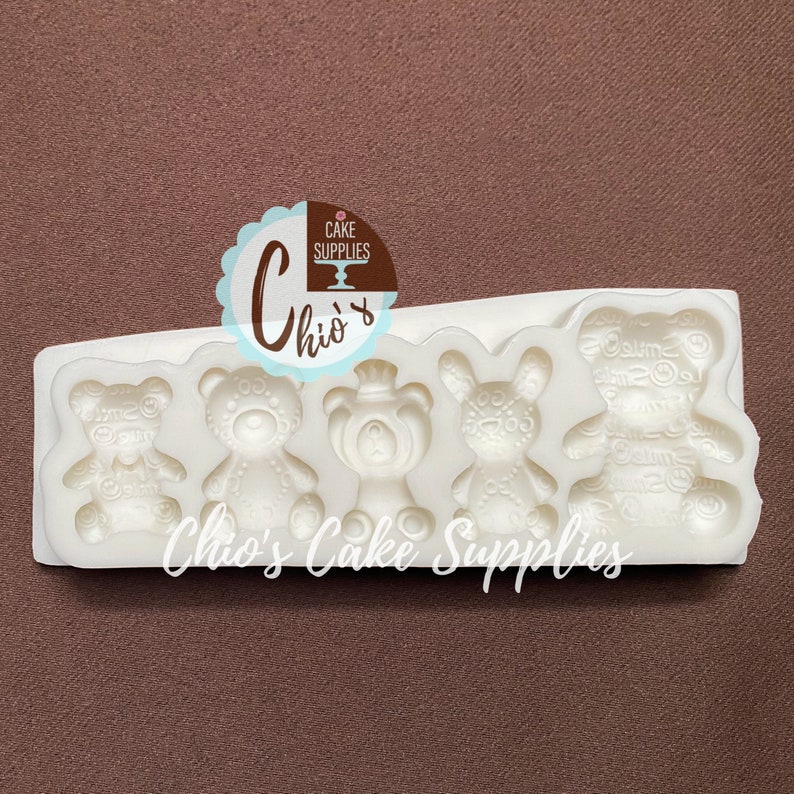 Pu&ograve; includere: Stampo in silicone con cinque cavit&agrave; a forma di orsacchiotti. Lo stampo &egrave; bianco e ha una superficie testurizzata. Lo stampo &egrave; etichettato "Chio's Cake Supplies".