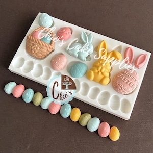 May include: A white silicone mold featuring cavities for Easter-themed shapes including bunnies, baskets, and eggs, with some finished pastel-colored egg-shaped pieces arranged in a row below the mold. The text Chio's Cake Supplies is visible.