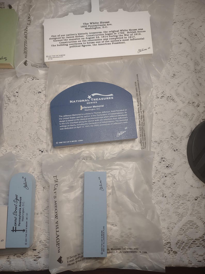 May include: A collection of souvenir cards and plaques featuring historical landmarks. The items include a card for the Jefferson Memorial, a plaque for the White House, and a sign for Famous Street Signs. Each item is in a plastic sleeve.