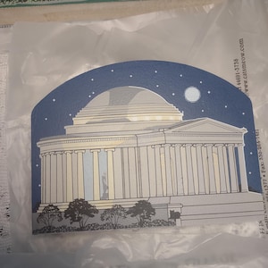May include: A decorative card featuring an illustration of a neoclassical building under a starry night sky with a full moon. The building has columns and a domed roof. The card is blue, white, and gray.