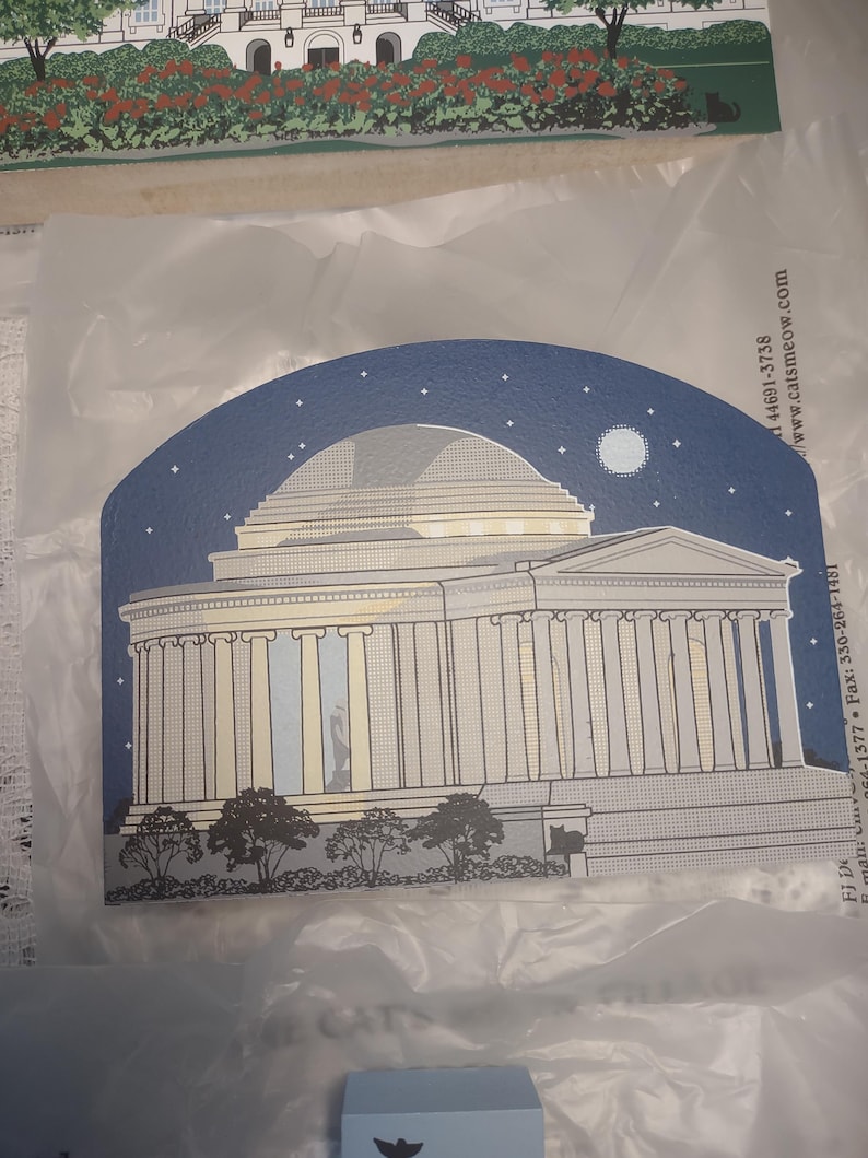 May include: A decorative card featuring an illustration of a neoclassical building under a starry night sky with a full moon. The building has columns and a domed roof. The card is blue, white, and gray.