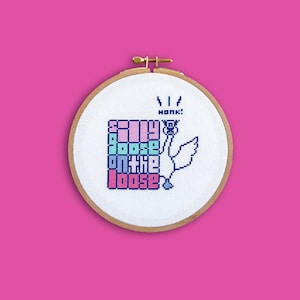 Könnte beinhalten: Ein weißer Kreuzstich-Stickrahmen mit einer weißen Gans und dem Text "Silly Goose on the Loose" in bunten Pixelbuchstaben. Die Gans hupt und hat ein kleines schwarzes Auge.