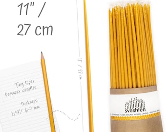 May include: A bundle of 100 thin, yellow beeswax taper candles, 11 inches long, in a brown paper tube with the brand name "sveshten" printed on the label. The label also states that the candles are eco-friendly, 100% natural beeswax candles, and made with honey.