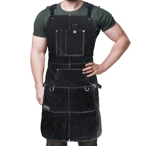 May include: Black leather apron with white stitching, featuring multiple pockets and adjustable straps. The apron has a chest pocket with a snap closure and two lower pockets with metal ring accents. A durable work apron for various tasks.
