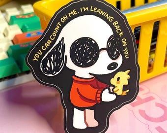 May include: A die-cut sticker featuring a cartoon dog wearing sunglasses and an orange sweater, holding a yellow bird. The sticker has the text "YOU CAN COUNT ON ME. I'M LEANING BACK ON YOU."