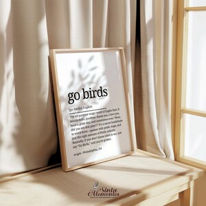 K&ouml;nnte beinhalten: Ein schwarz-wei&szlig;er druckbarer Wandkunstdruck mit dem Text "go birds", definiert als "Das Allzweck-Zauberwort der Eagles-Fans. Es bedeutet Hallo, Auf Wiedersehen, Danke, Ich liebe dich, Sch&ouml;nen Tag noch, und manchmal sogar "Wow, hast du das Spiel gesehen?!" Es ist ein geheimer Handschlag in Wortform - gesprochen mit Stolz, Hoffnung und genau der richtigen Menge an Philly-Einstellung. Im Grunde genommen, wenn du nicht wei&szlig;t, was du sagen sollst, sag einfach "Go Birds," und du bist golden Herkunft: Philadelphia, PA"