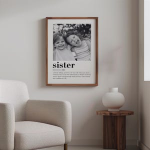 May include: Black and white photograph of two sisters smiling and laughing. The photo is framed and has the word "sister" with a definition below it.