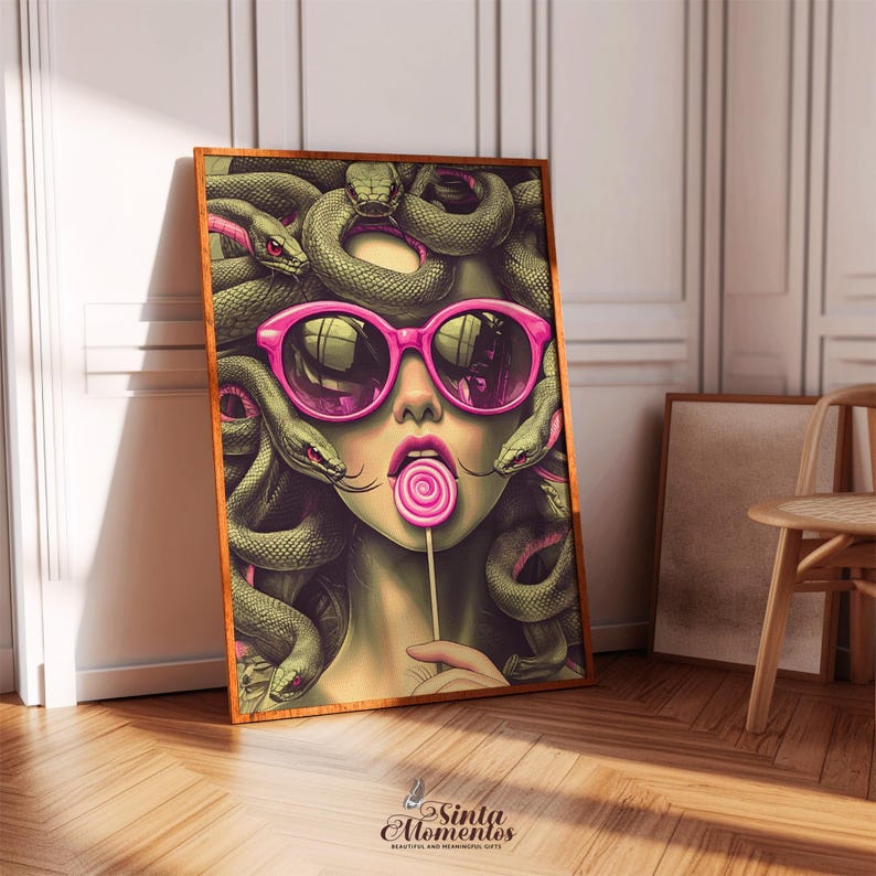 May include: A framed art print featuring a stylized illustration of Medusa wearing pink sunglasses and holding a lollipop. Her hair is composed of green snakes with red accents. The artwork has a wooden frame and is displayed in a room with a wooden floor.