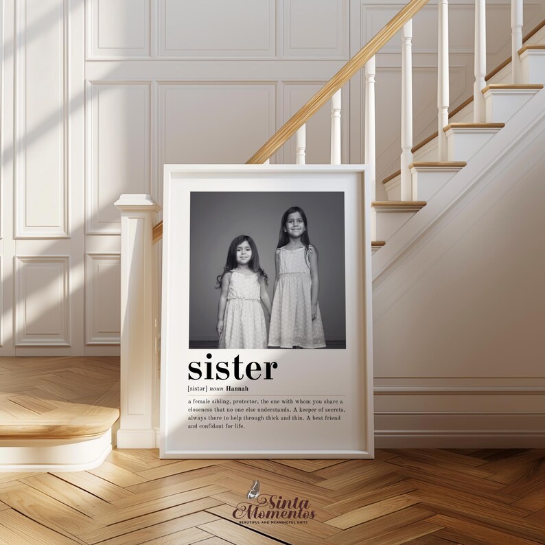 May include: Black and white photograph of two sisters standing side by side. The photo is framed in a white frame and has a definition of the word "sister" below the photo. The definition reads: "[sister] noun Hannah. A female sibling, protector, the one with whom you share a closeness that no one else understands. A keeper of secrets. Always there to help through thick and thin. A best friend and confidant for life."