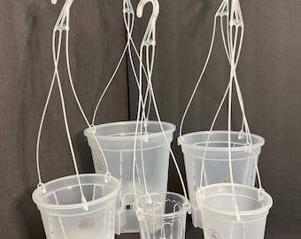 May include: A collection of clear plastic hanging plant pots in various sizes. Each pot has a white plastic hook and hanging wires. The pots are designed with drainage holes and a textured surface. The background is a solid dark gray.