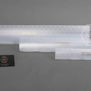 May include: Three clear plastic storage containers with a honeycomb pattern on the top and the text "The Moss Pole" printed on the front of each container.
