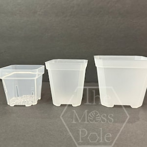 May include: Three clear plastic square pots of different sizes. The pots have a square base and a square top with rounded edges. The pots are made of a translucent plastic material.