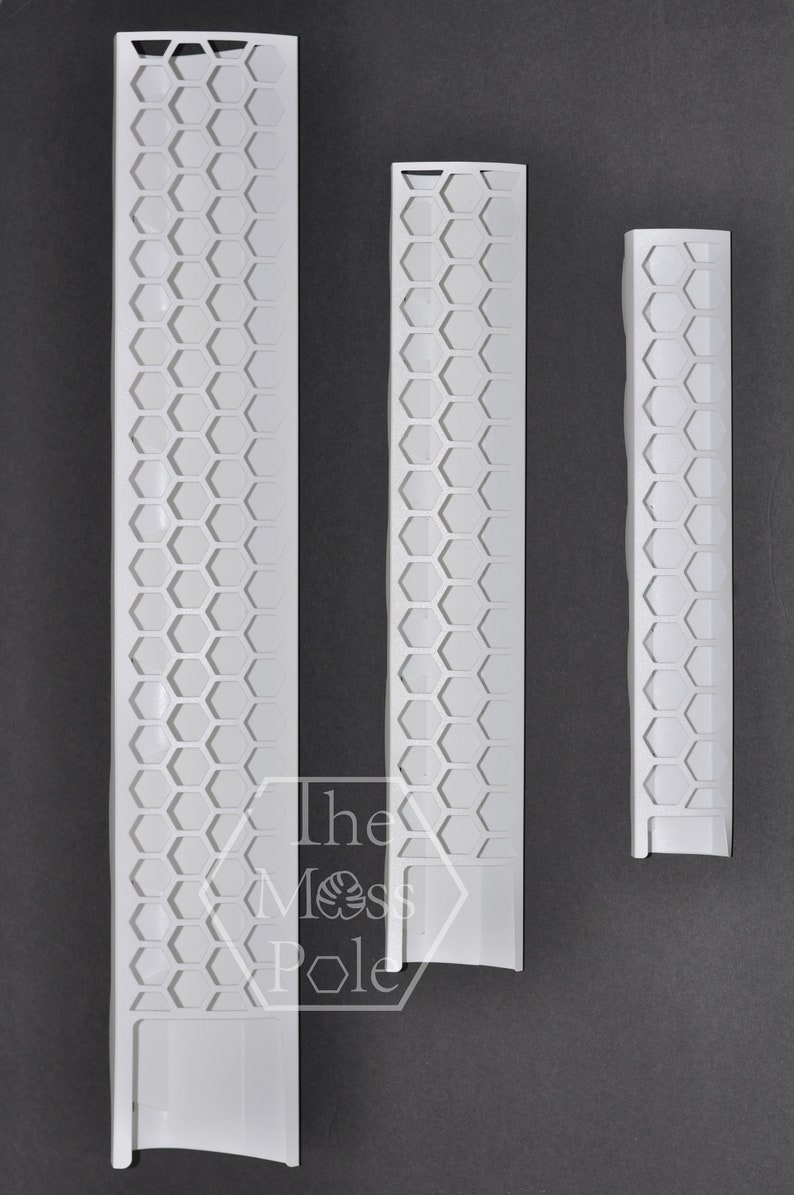 May include: Three white plastic honeycomb-patterned wall trim pieces. The trim pieces are different lengths. The text "The Moss Pole" is visible in the image.