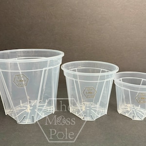 May include: Three clear plastic pots with drainage holes and the text "The Moss Pole" printed on the side. The pots are different sizes.