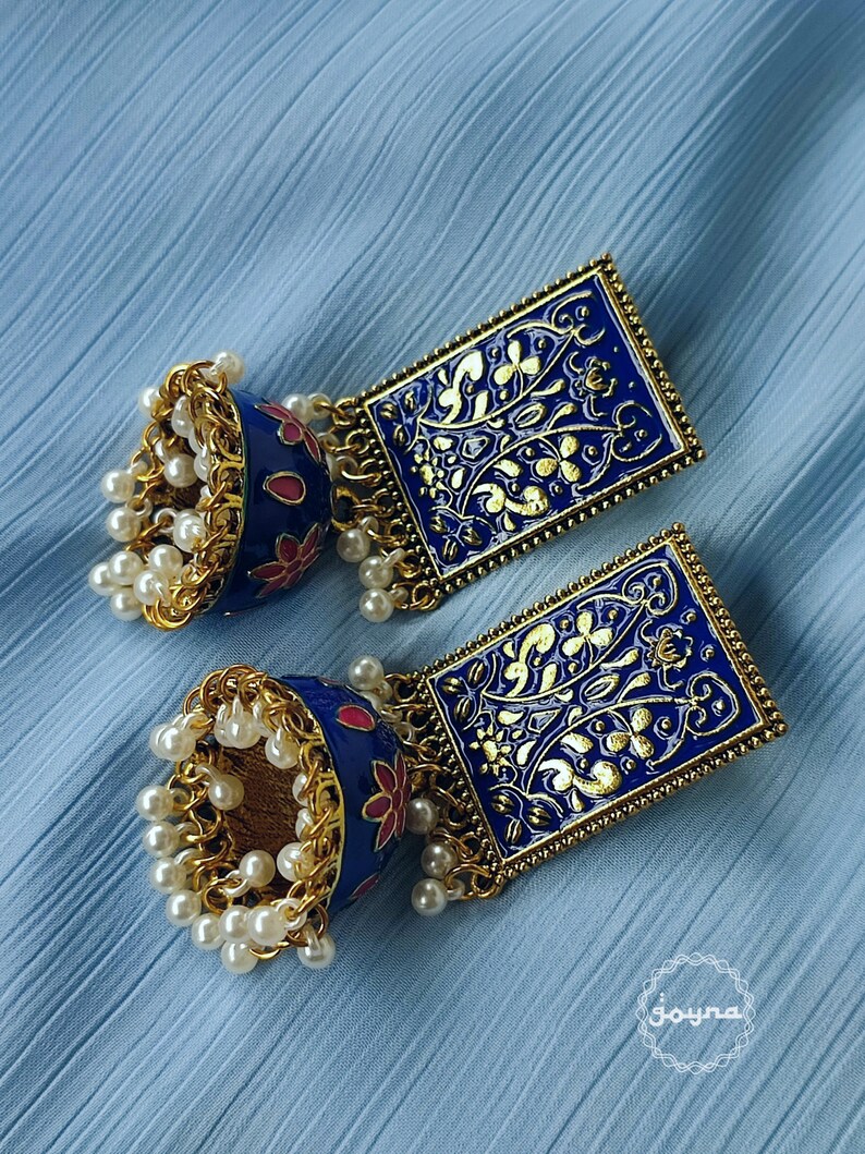 Pode incluir: Um par de brincos azuis e dourados com um design floral. Os brincos t&ecirc;m um charme pendurado com uma corrente de contas de p&eacute;rola.