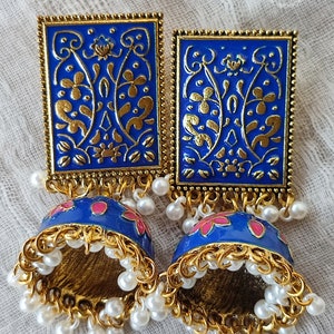 Pode incluir: Um par de brincos azuis e dourados com um design floral. Os brincos s&atilde;o feitos de metal e t&ecirc;m uma forma de sino pendente com detalhes de p&eacute;rolas brancas.