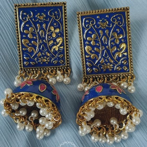 Pode incluir: Um par de brincos azuis e dourados com um design floral. Os brincos s&atilde;o feitos de metal e t&ecirc;m uma forma de sino pendente com detalhes de p&eacute;rolas.