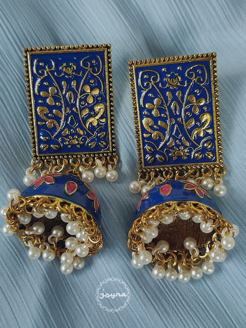 Pode incluir: Um par de brincos azuis e dourados com um design floral. Os brincos s&atilde;o feitos de metal e t&ecirc;m uma forma de sino pendente com detalhes de p&eacute;rolas.