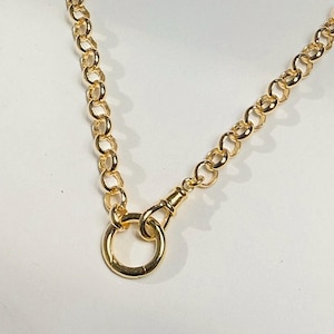 May include: A gold-toned chain necklace featuring round, interlocking links. The necklace includes a prominent circular ring clasp connected to the chain by a small, spring-loaded swivel hook mechanism, creating a secure and functional closure.