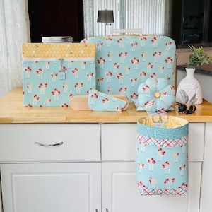 May include: A collection of handmade fabric items, including a sewing machine cover, a zippered pouch, a pencil case, a pincushion, and a hanging basket. The items feature a light blue floral pattern with red flowers and a yellow honeycomb pattern.
