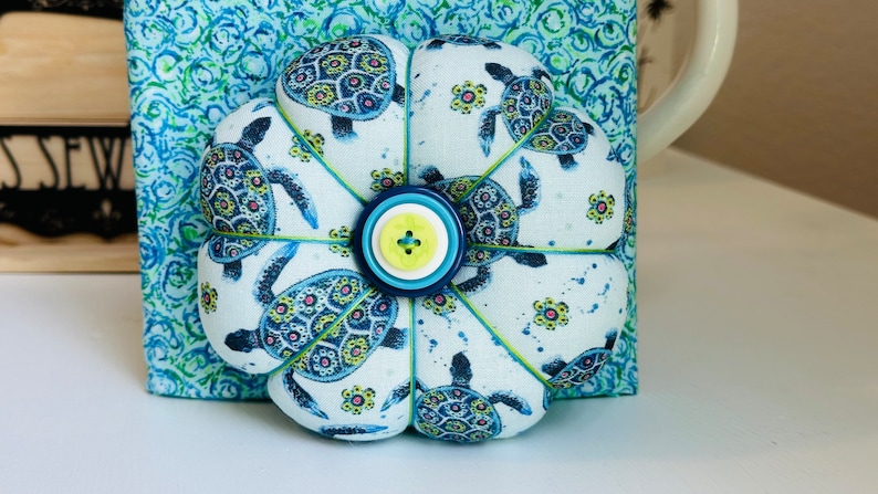 This beautiful Sea Turtles cushion in beachy blues and greens has ocean swirl on the back and anchor buttons on both sides.Anyone who enjoys the ocean or these amazing creatures would love this pincushion.