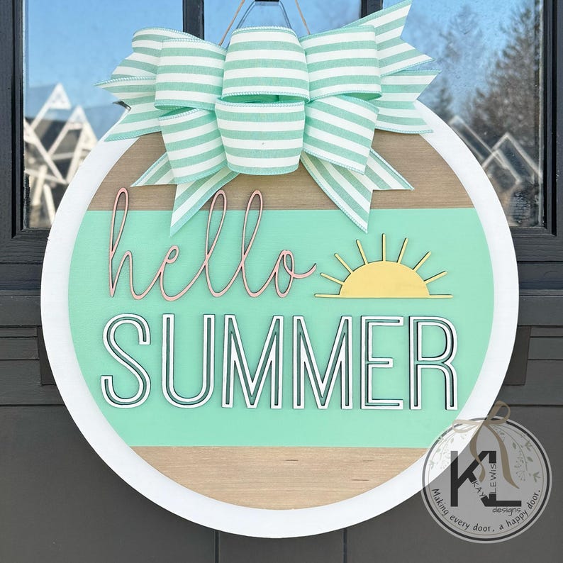 May include: A round wooden door hanger with a white border. The background is a light green with a brown wood grain stripe. The words "hello summer" are written in black with a white outline. A yellow sun with rays is to the right of the words. A green and white striped bow is at the top of the hanger.